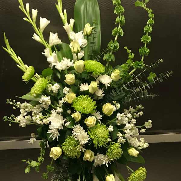 Tall green and white standing spray with roses, mums, and bells of Ireland on a metal easel