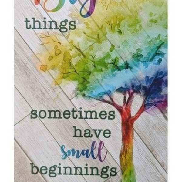 Decorative sign with rainbow tree and the words 'Big things sometimes have small beginnings' on a wood plank background