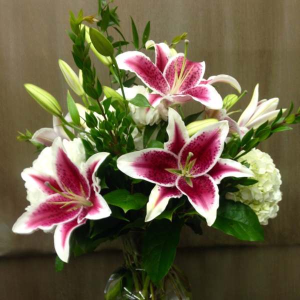 Pink stargazer lilies and white flowers in a glass vase