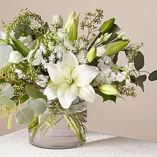 White lilies and green buds in a clear glass vase