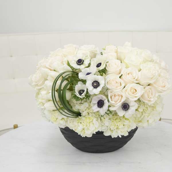 White rose and anemone arrangement in a black bowl vase