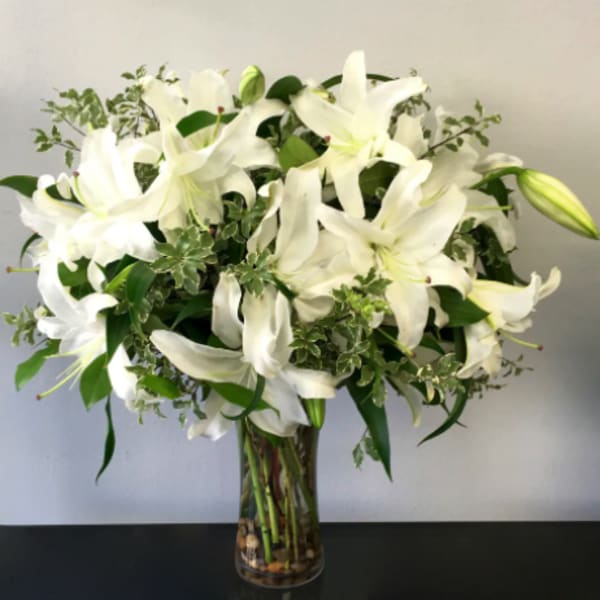 White lilies arranged in a clear glass vase