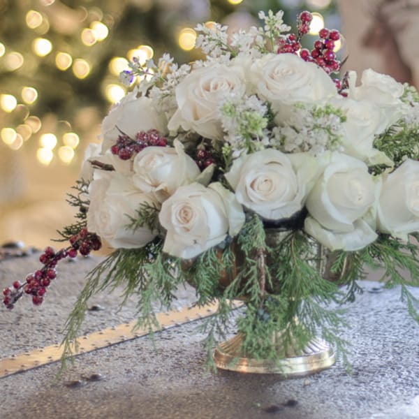 White rose bouquet with red berry accents in a gold vase
