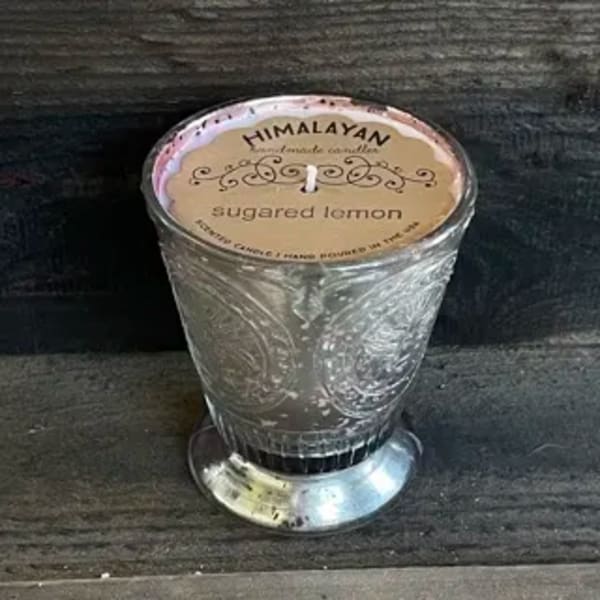 A glass candle in an embossed holder labeled sugared lemon