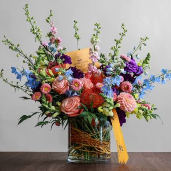 Colorful mixed bouquet in a clear glass vase with a yellow ribbon