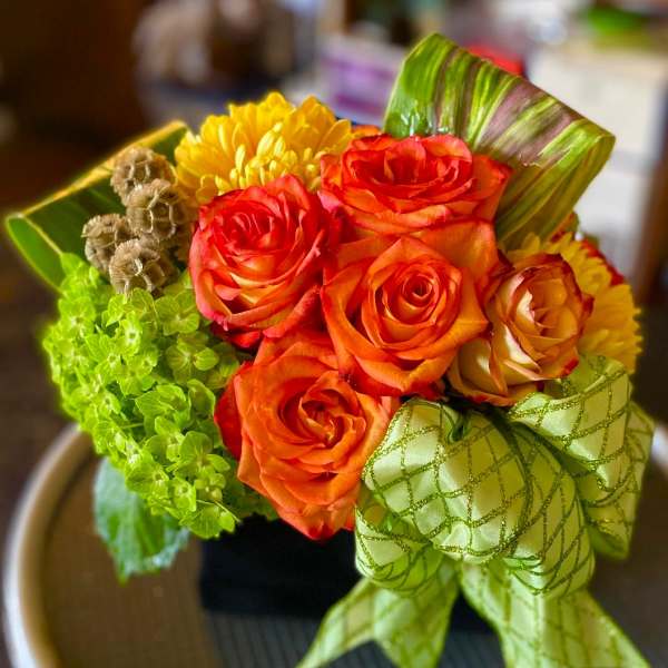 Bouquet of orange roses and yellow mums with a green ribbon bow