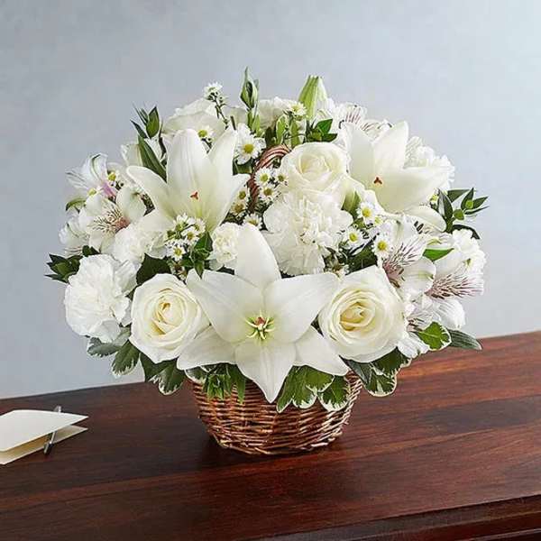 White lilies and roses arranged in a wicker basket