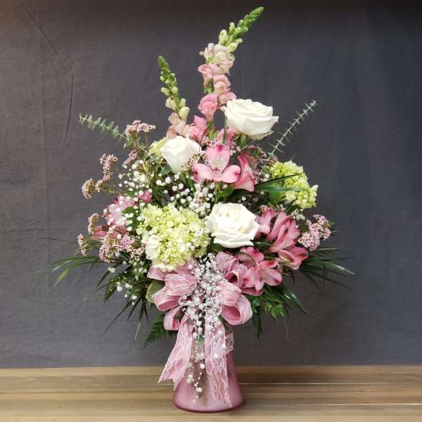 Pink and white floral arrangement in a pink vase with lace ribbon