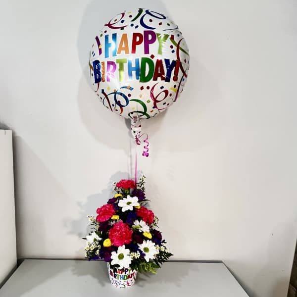 Birthday balloon above a colorful flower arrangement in a printed cup