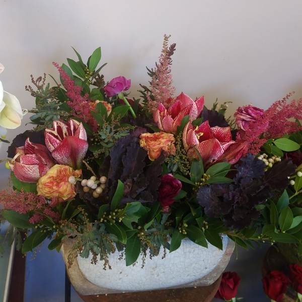 Mixed floral arrangement with pink and red blooms in a white vase