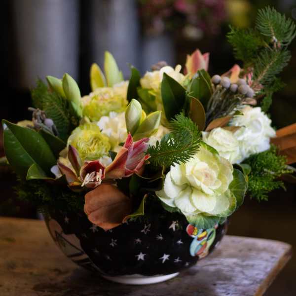 Mixed floral arrangement in a black bowl with white star pattern