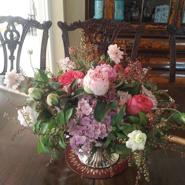 Pink and white rose arrangement in a silver vase on a table
