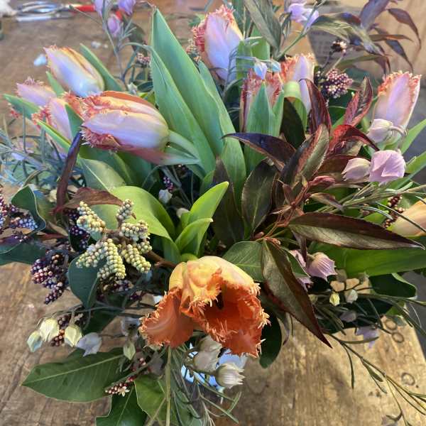 Bouquet of fringed tulips and mixed foliage on a table
