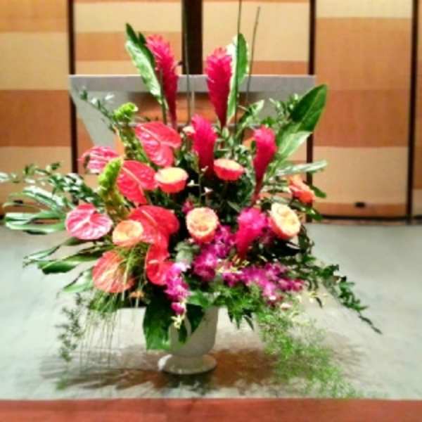 Large pink floral arrangement in a white pedestal vase