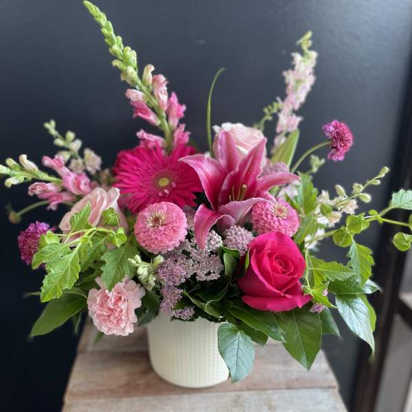 Pink mixed flower arrangement in a white vase