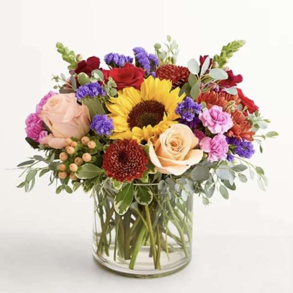Mixed bouquet with a sunflower and roses in a clear glass vase
