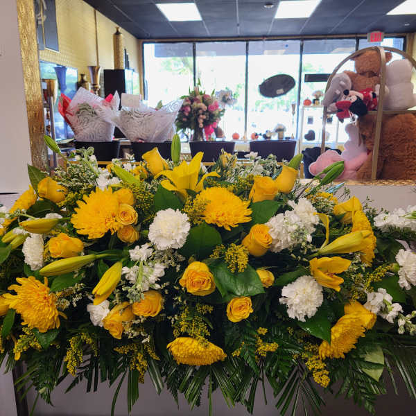 Large yellow and white floral arrangement with roses, lilies, and chrysanthemums
