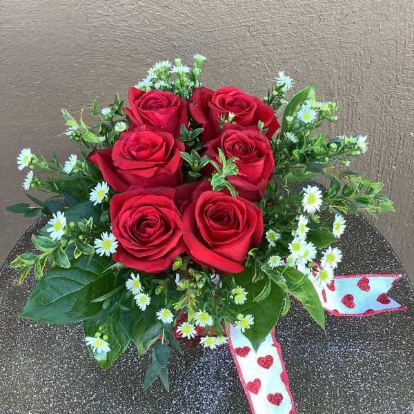 Red roses with small white daisies and a heart ribbon