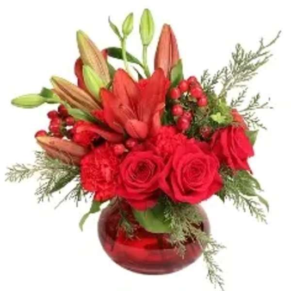 Red roses and lilies arranged in a red glass vase