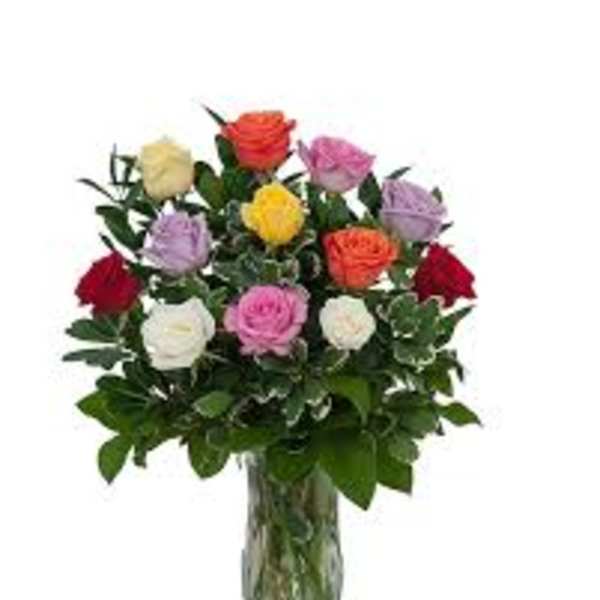 Mixed-color rose arrangement in a clear glass vase with lush foliage