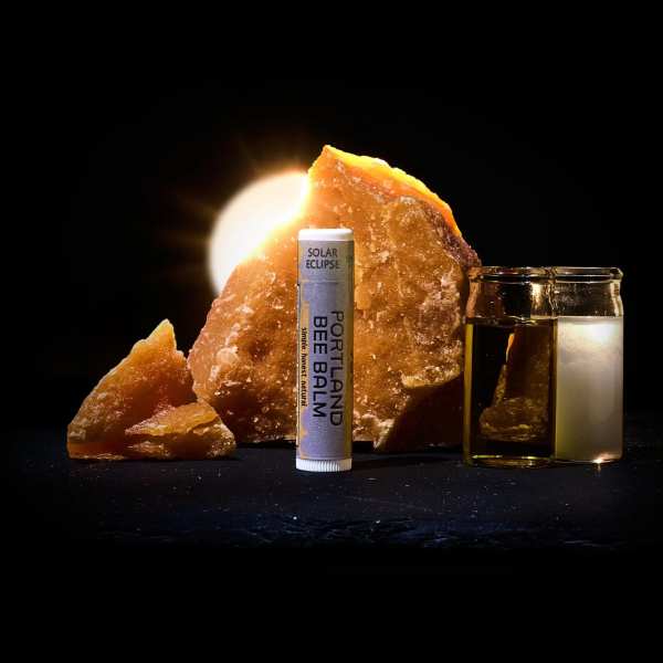 Lip balm tube beside amber glass jars and orange crystal pieces