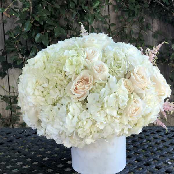 White hydrangea and blush rose arrangement in a white vase