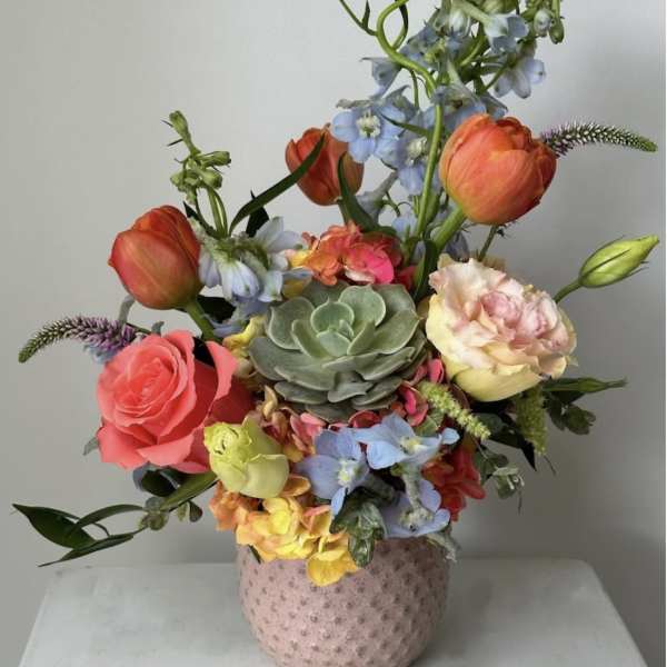 Mixed bouquet with roses, tulips, succulents, and blue flowers in a pink vase