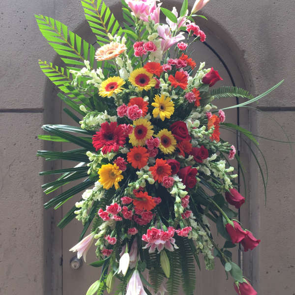 Tall standing floral spray with red, yellow, and pink blooms