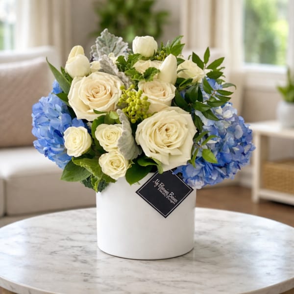White roses and blue hydrangeas in a white hatbox