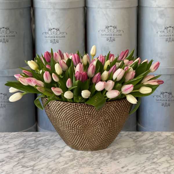 Pink and white tulips arranged in a gold textured vase