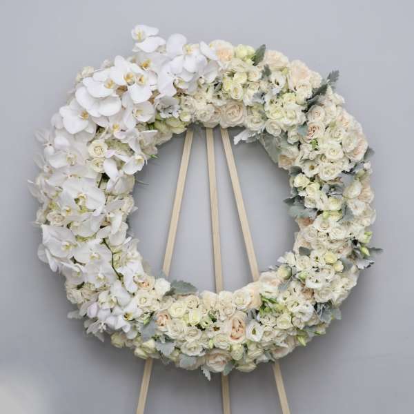 Large white floral wreath on a wooden easel