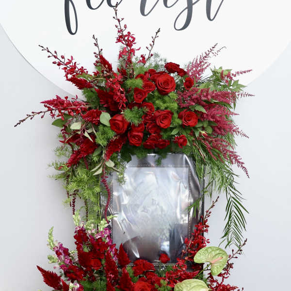 Large red floral standing spray on an easel with a framed center
