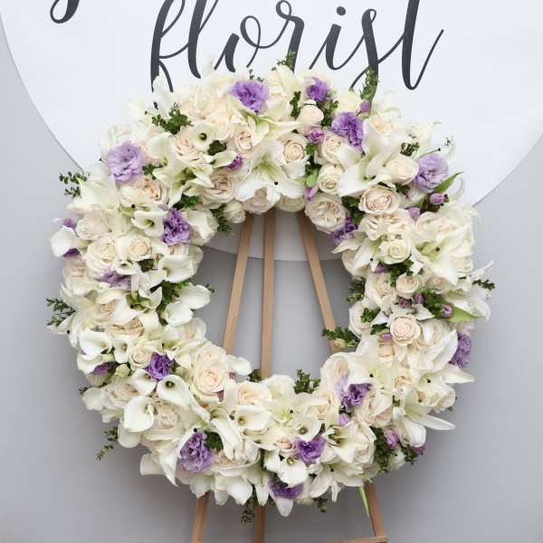 Large floral wreath of white and pale lavender flowers on an easel