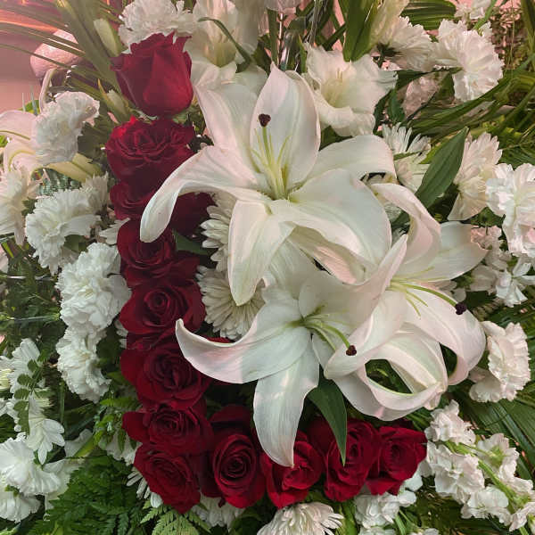 Red roses and white lilies arranged with white carnations