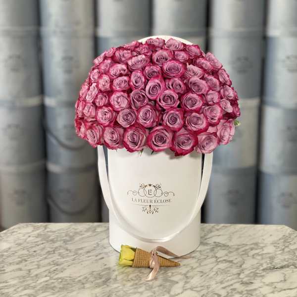 Pink rose arrangement in a white hatbox with a single rose boutonniere in front