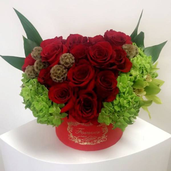 Red roses and green hydrangeas in a red round box