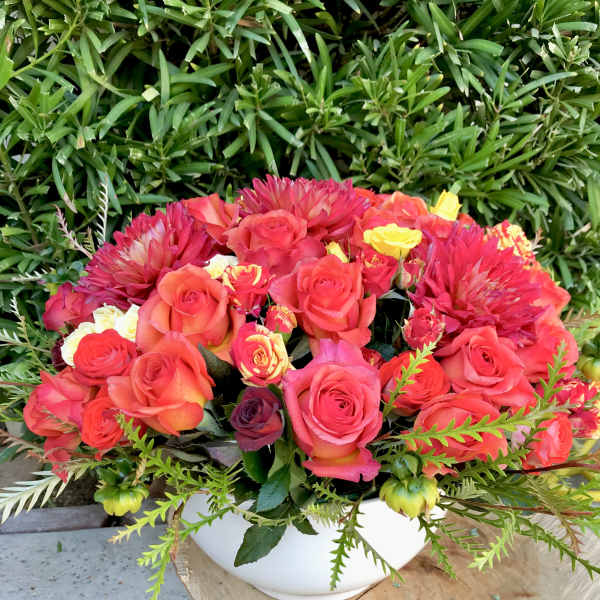 Bouquet of pink and coral roses in a white bowl vase