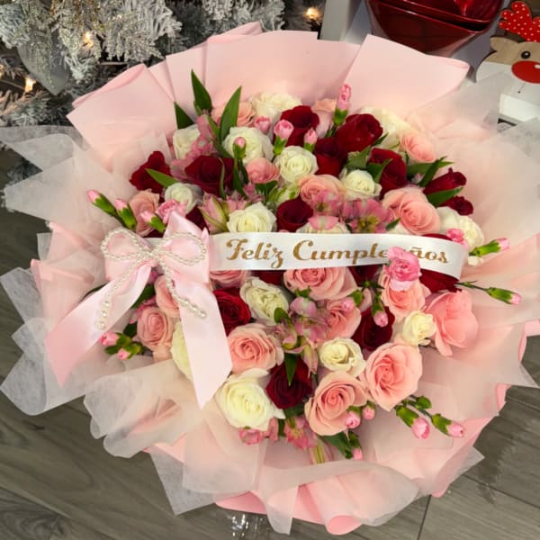 Bouquet of pink, red, and white roses with a pink ribbon