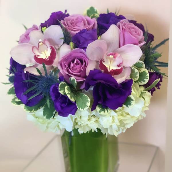 Purple and pink bouquet in a square glass vase