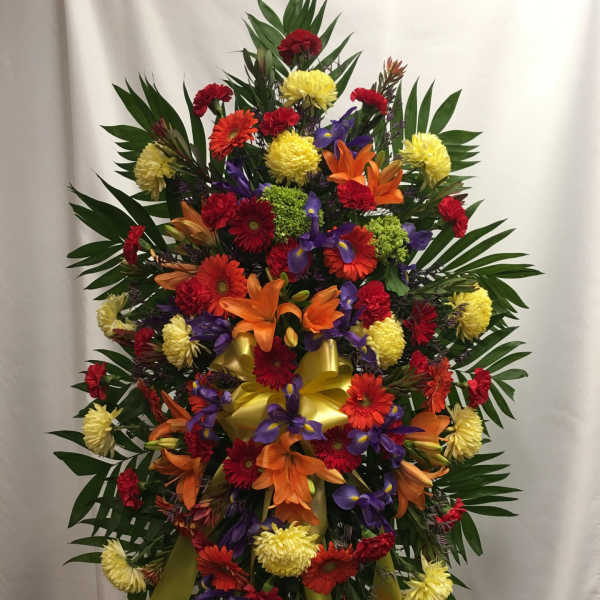 Large standing spray with mixed bright flowers and a yellow ribbon