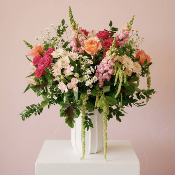 Mixed bouquet of pink, peach, and white flowers in a white vase