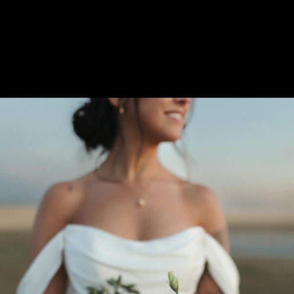 Bride holding a white and green bouquet with roses and thistle
