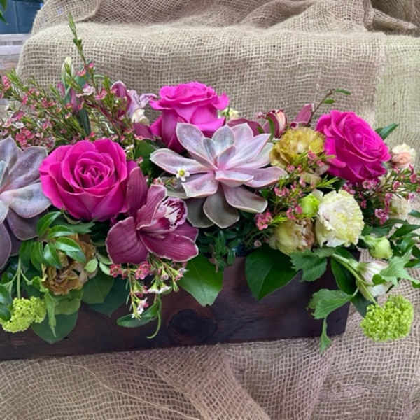 Pink roses and succulents arranged in a wooden box