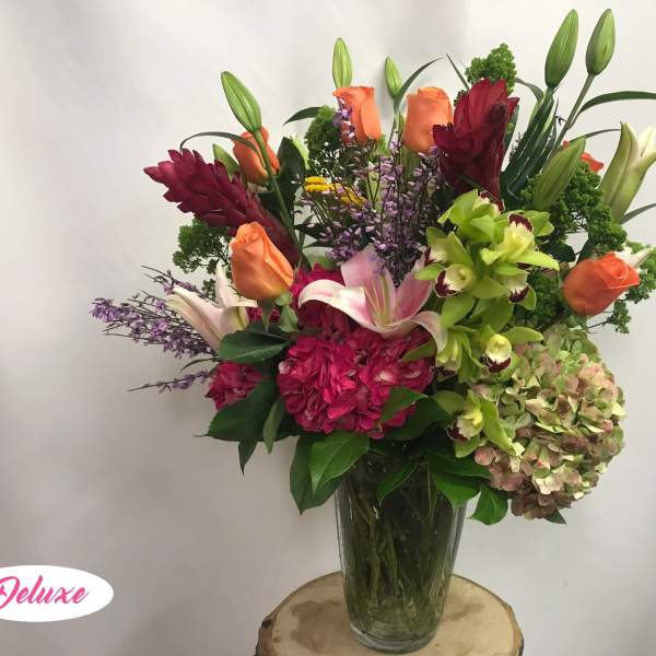 Mixed bouquet of lilies, roses, orchids, and hydrangea in a glass vase