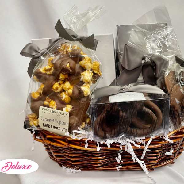 Gift basket with wrapped chocolates and caramel popcorn in a wicker basket