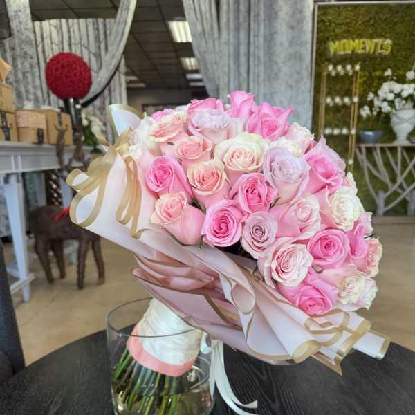 Bouquet of pink and white roses wrapped in pale paper