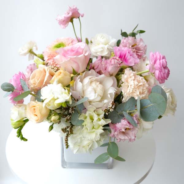 Mixed pink and white bouquet in a clear square vase