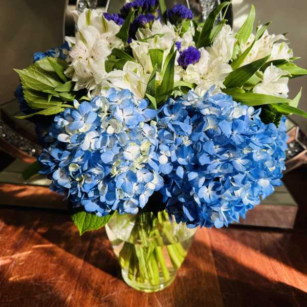 Blue and white hydrangea bouquet in a clear glass vase