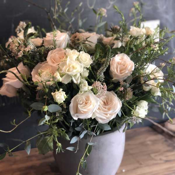 Blush and white roses arranged in a gray vase