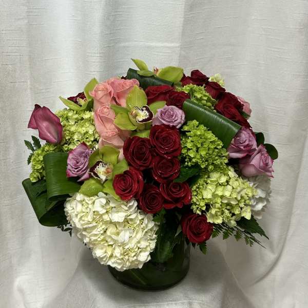 Mixed bouquet of red, pink, and white flowers in a glass vase